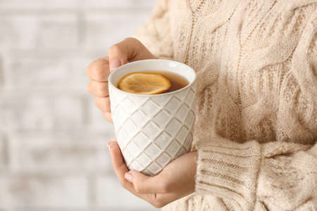 Young woman drinking hot tea at home, closeup