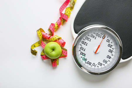 Scales and measuring tapes with apple on white background. Weight loss concept