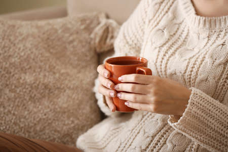 Young woman drinking hot tea at home, closeupの写真素材