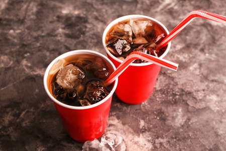 Cups of cold cola on gray background