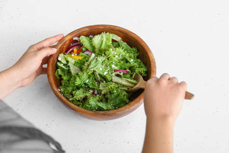 Woman preparing fresh salad at table, closeup