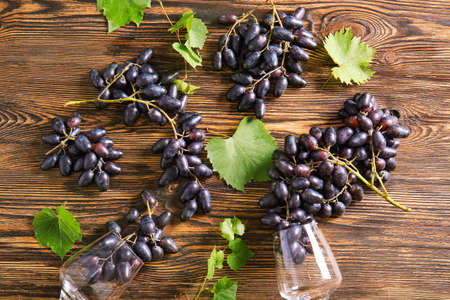 Sweet grapes with wineglasses on wooden table