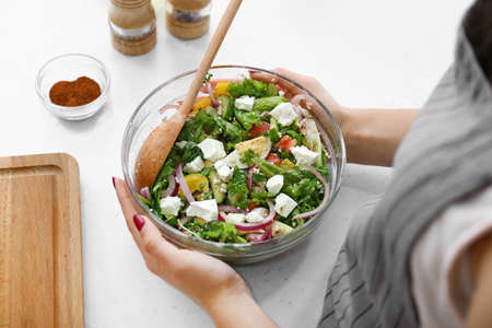Woman with fresh salad in bowl at table, closeupの写真素材