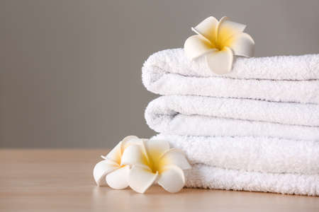 Stack of clean towels with flowers on table against gray backgroundの写真素材
