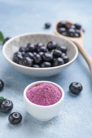Acai berries with powder on color background