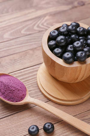 Acai berries with powder on wooden background