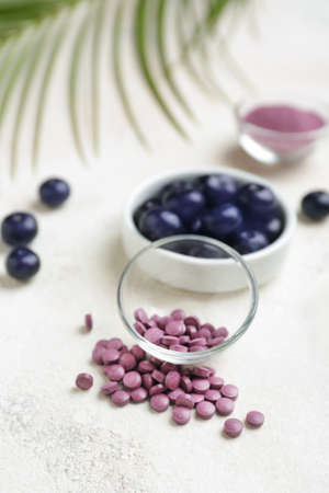 Acai berries with tablets on white backgroundの写真素材