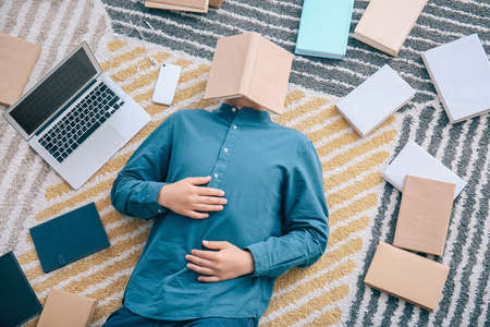 Asian student with a lot of books and laptop preparing for exam at home