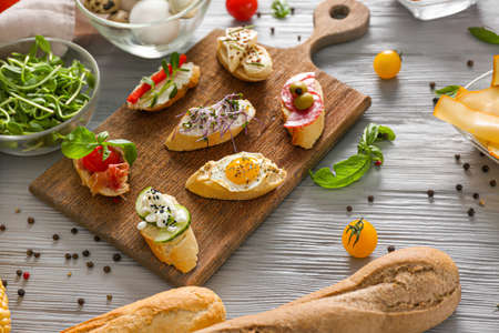 Board with different tasty sandwiches on wooden tableの写真素材