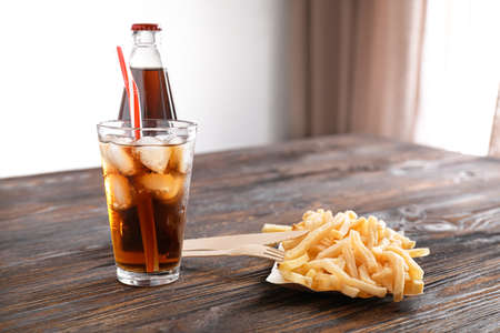 Cold cola and tasty french fries on wooden table
