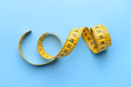 Measuring tape on color background