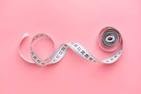 Measuring tape on color background