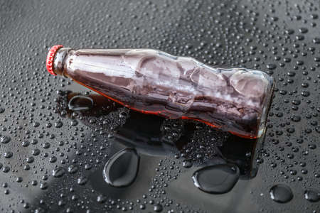 Bottle of cold cola on dark tableの写真素材
