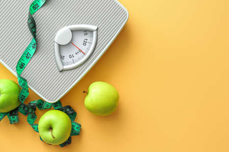 Scales, apples and measuring tape on color background. Weight loss conceptの写真素材