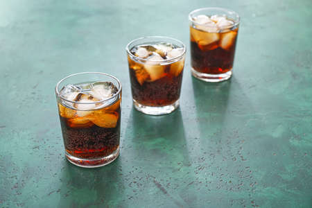 Glasses of cold cola on color table