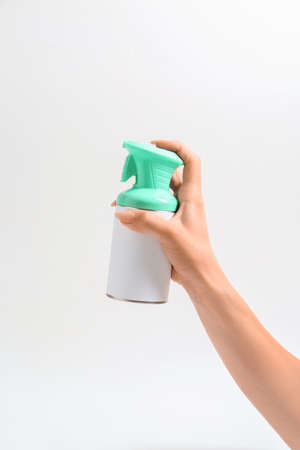Female hand with bottle of air freshener on light backgroundの写真素材