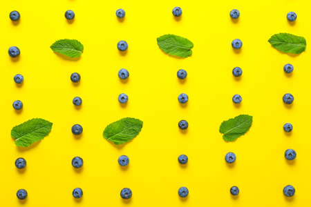 Many sweet ripe blueberries and mint leaves on color background