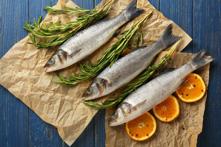 Fresh seabass fish with orange and rosemary on wooden backgroundの写真素材