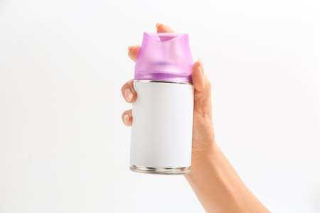 Female hand with bottle of air freshener on light background