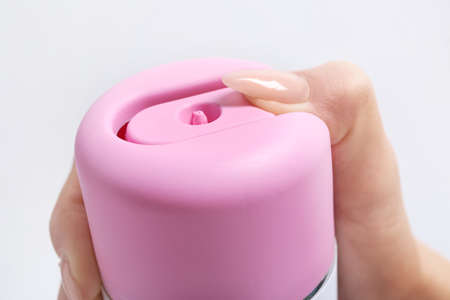 Female hand with bottle of air freshener on light background, closeup