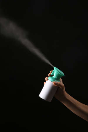 Female hand with bottle of air freshener on dark backgroundの写真素材