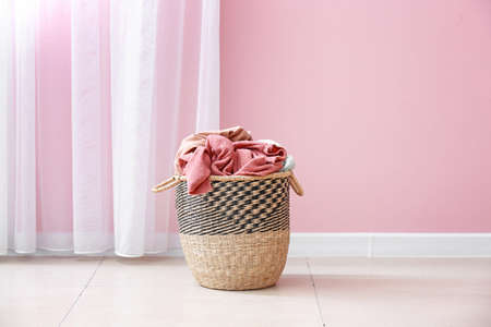 Basket with laundry on floor near color wallの写真素材
