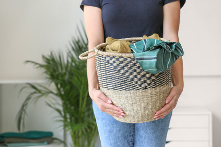 Woman holding basket with laundry at homeの写真素材