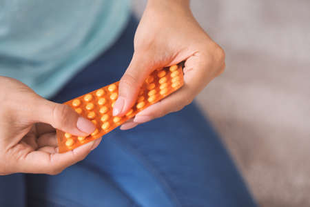 Young woman with pills at home, closeup