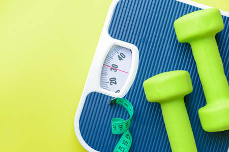 Scales, dumbbells and measuring tape on color background. Weight loss conceptの写真素材