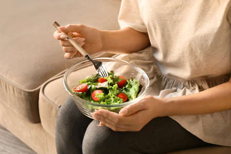 Woman eating tasty salad at home, closeupの写真素材