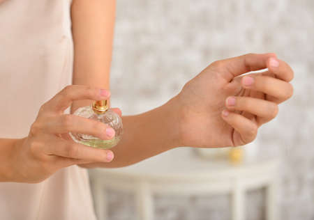 Young woman with bottle of perfume at home