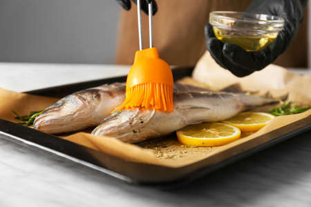 Woman cooking sea bass at table, closeupの写真素材