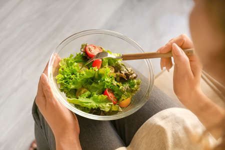 Woman eating tasty vegetable salad at home, closeupの写真素材