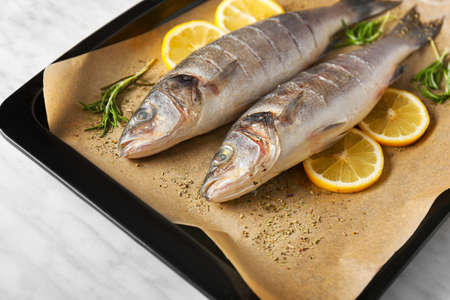 Fresh sea bass with spices and lemon on tray