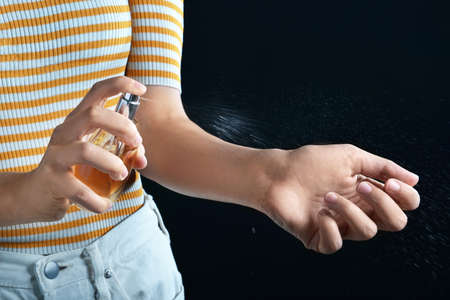 Young woman with bottle of perfume on dark background, closeupの写真素材