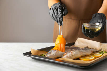 Woman cooking sea bass at table, closeup