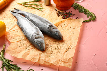 Raw sea bass with herbs and spices on color background