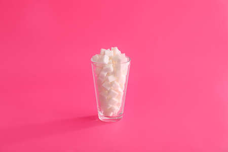 Glass with sugar cubes on color backgroundの写真素材