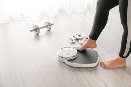 Woman with scales and dumbbells at home. Weight loss conceptの写真素材