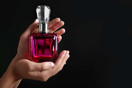 Female hands with bottle of perfume on dark backgroundの写真素材