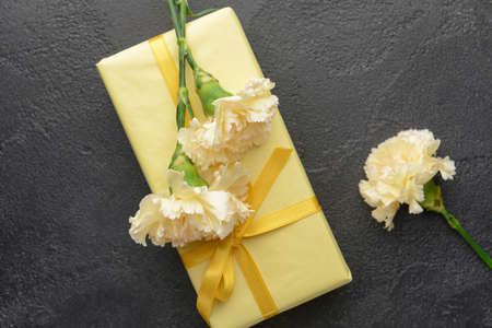 Gift box with beautiful carnation flowers on dark background