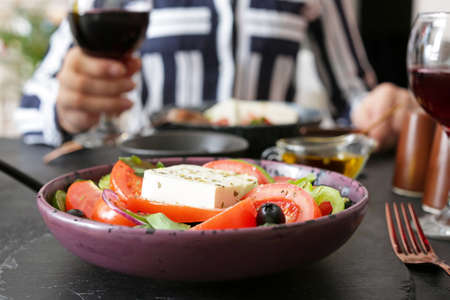 Plate with tasty Greek salad on table