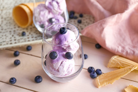 Glass with tasty blueberry ice cream on wooden table