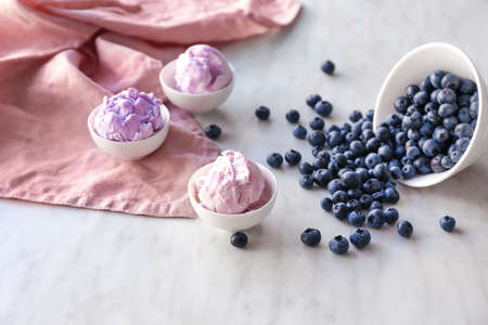 Bowls with tasty blueberry ice cream on light table