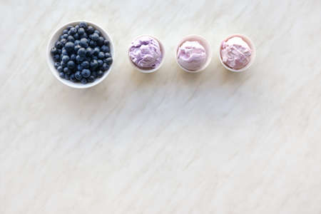 Bowls with tasty blueberry ice cream on light background