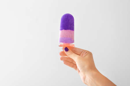 Female hand with tasty blueberry ice cream on white backgroundの写真素材