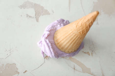 Wafer cone with tasty blueberry ice cream on white background