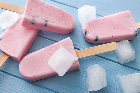 Tasty blueberry ice cream with ice cubes on wooden table