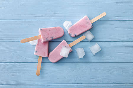 Tasty blueberry ice cream with ice cubes on wooden table
