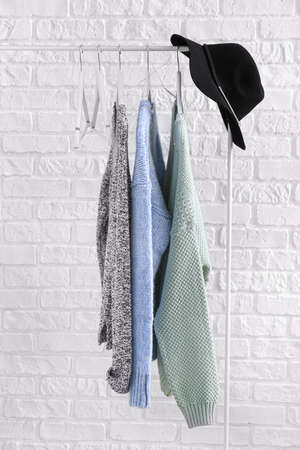 Rack with winter clothes near white brick wallの写真素材